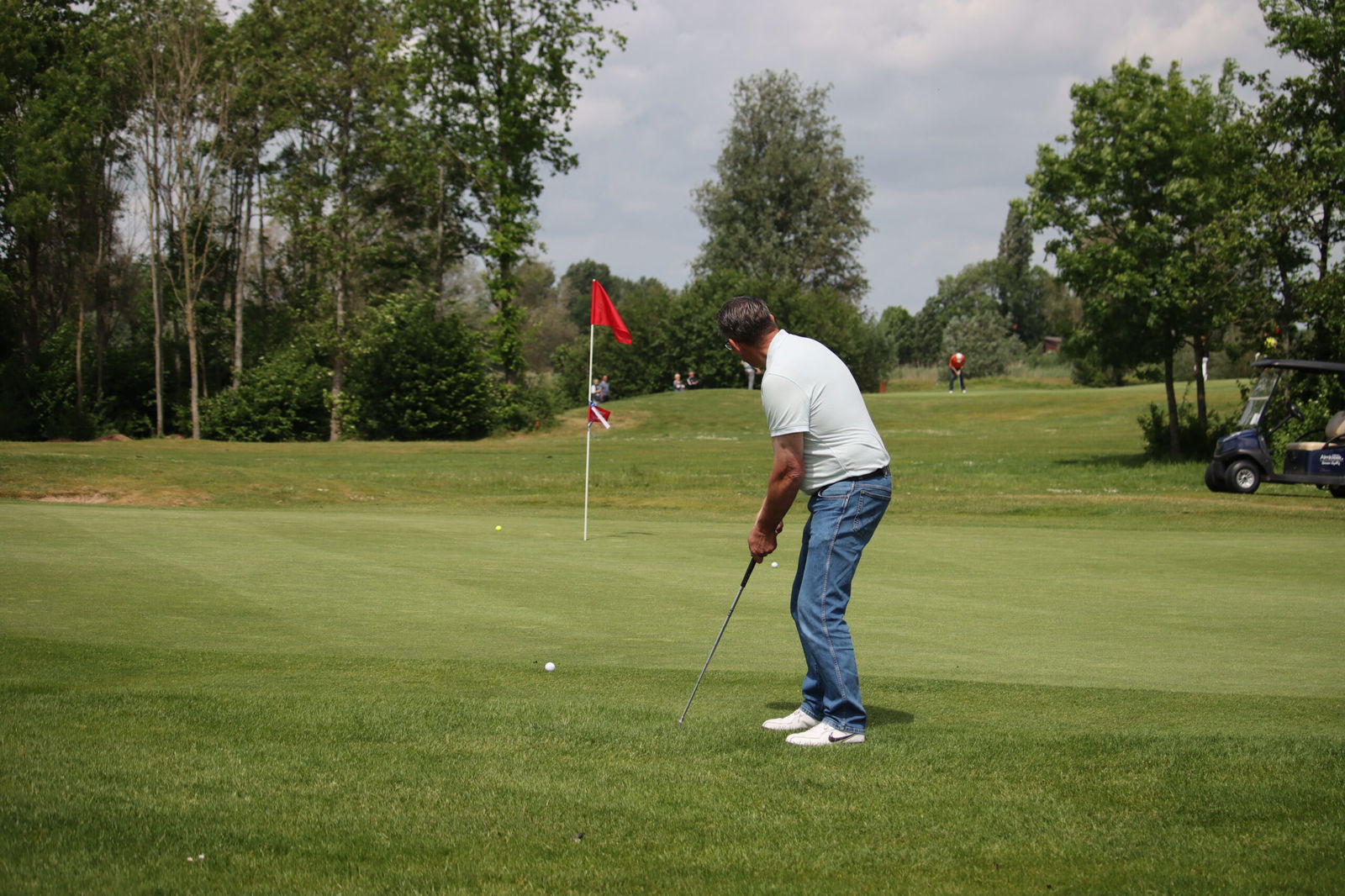 Golfer chipt naar de green op de shortgolfbaan van Golfpark Almkreek met vlag op de achtergrond