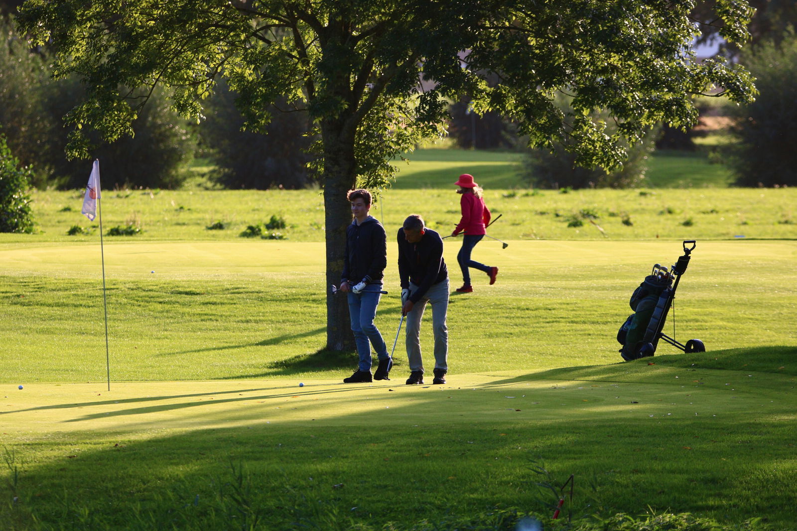 Golfers spelen en putten op de green van Golfpark Almkreek in de zon